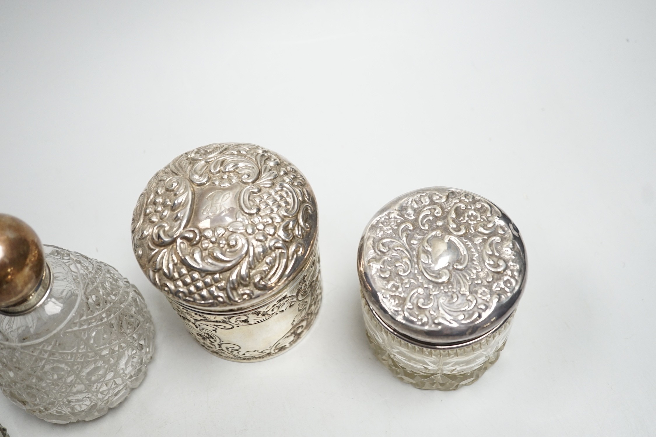 Two repousse silver lidded toilet jars, including glass, largest, 95mm and two silver mounted glass scent bottles.